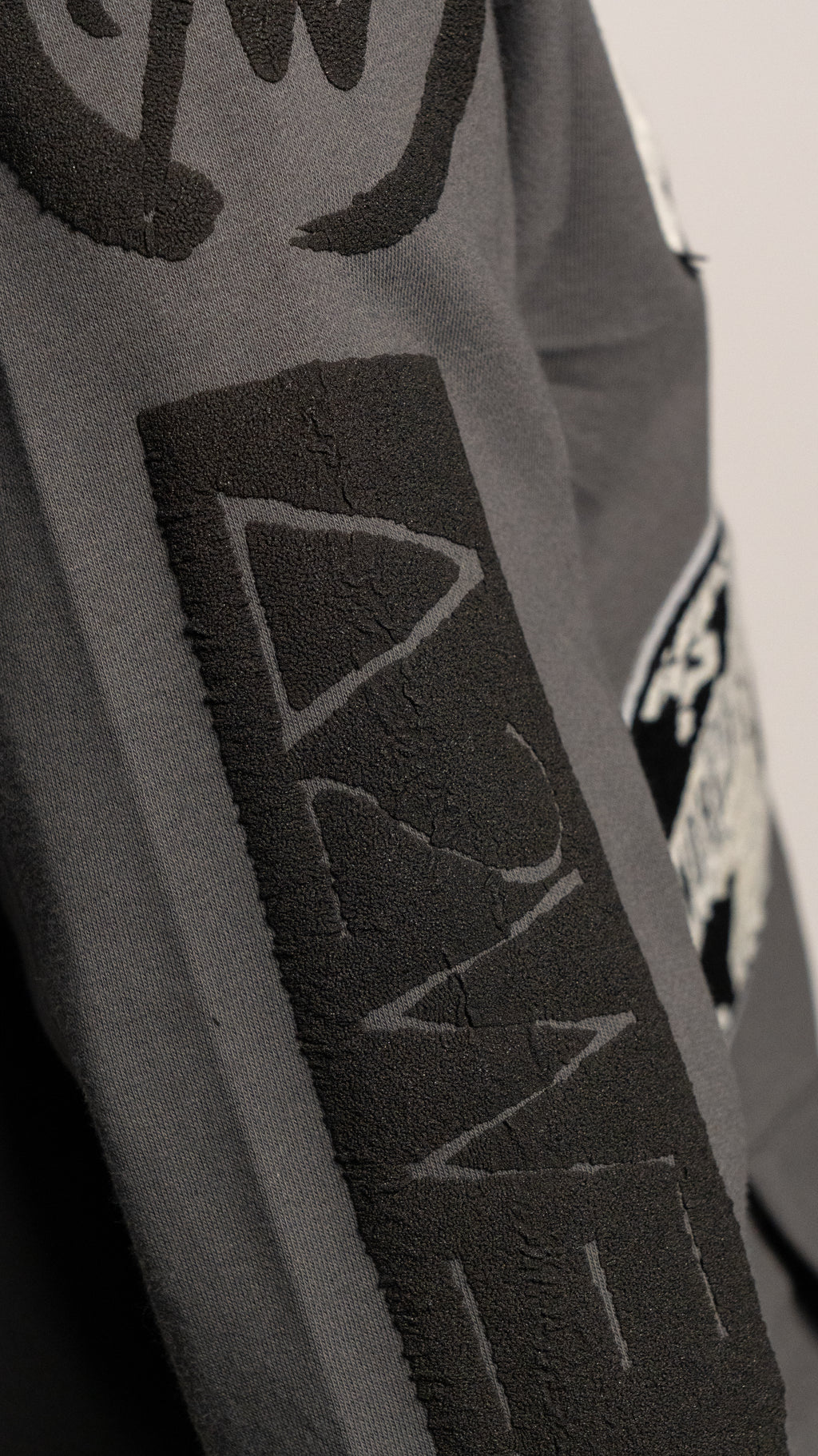 Close-up of a gray jacket with Art to wear logo on a plain background