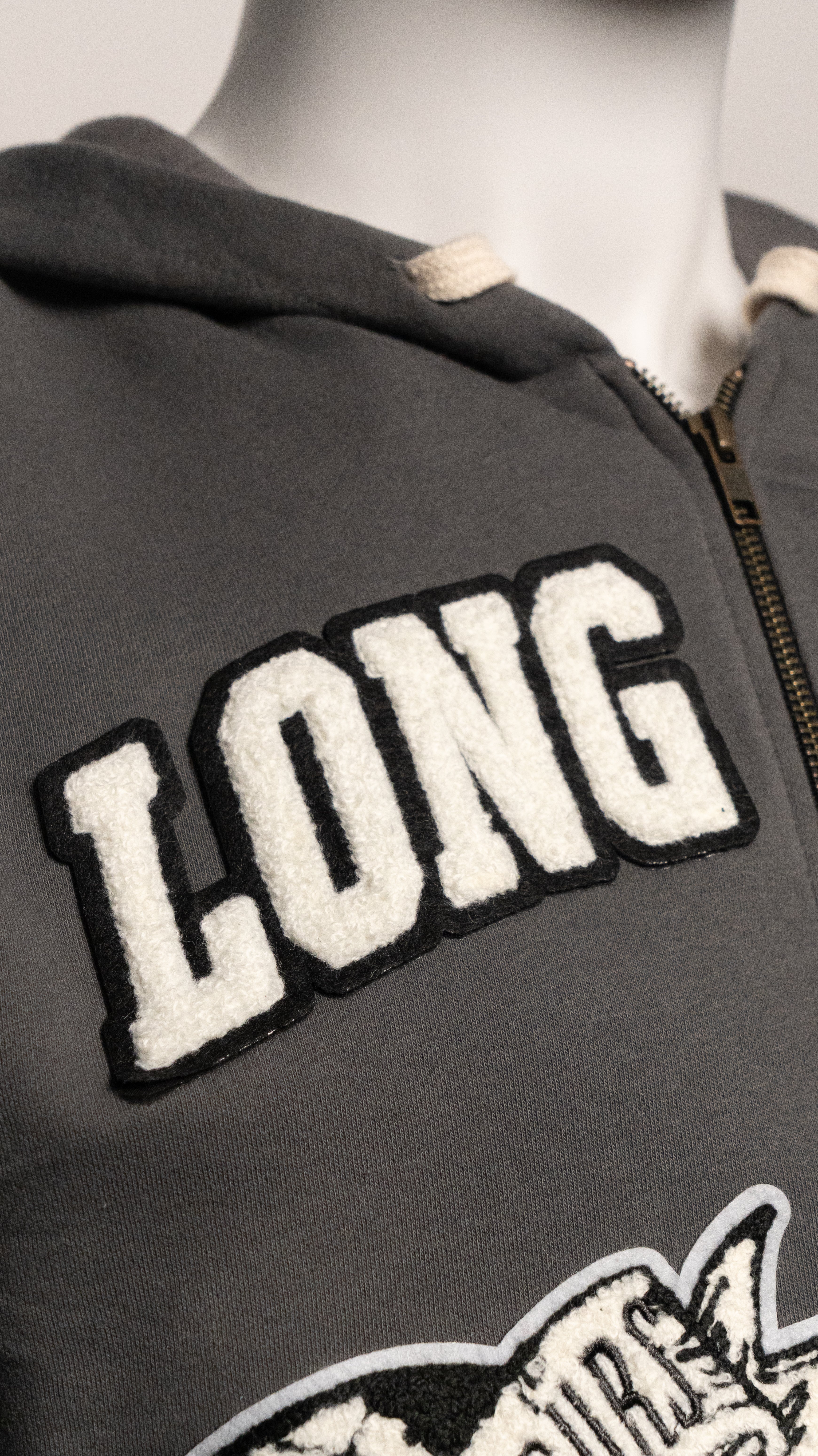 Gray jacket with 'LONG' patch on a mannequin