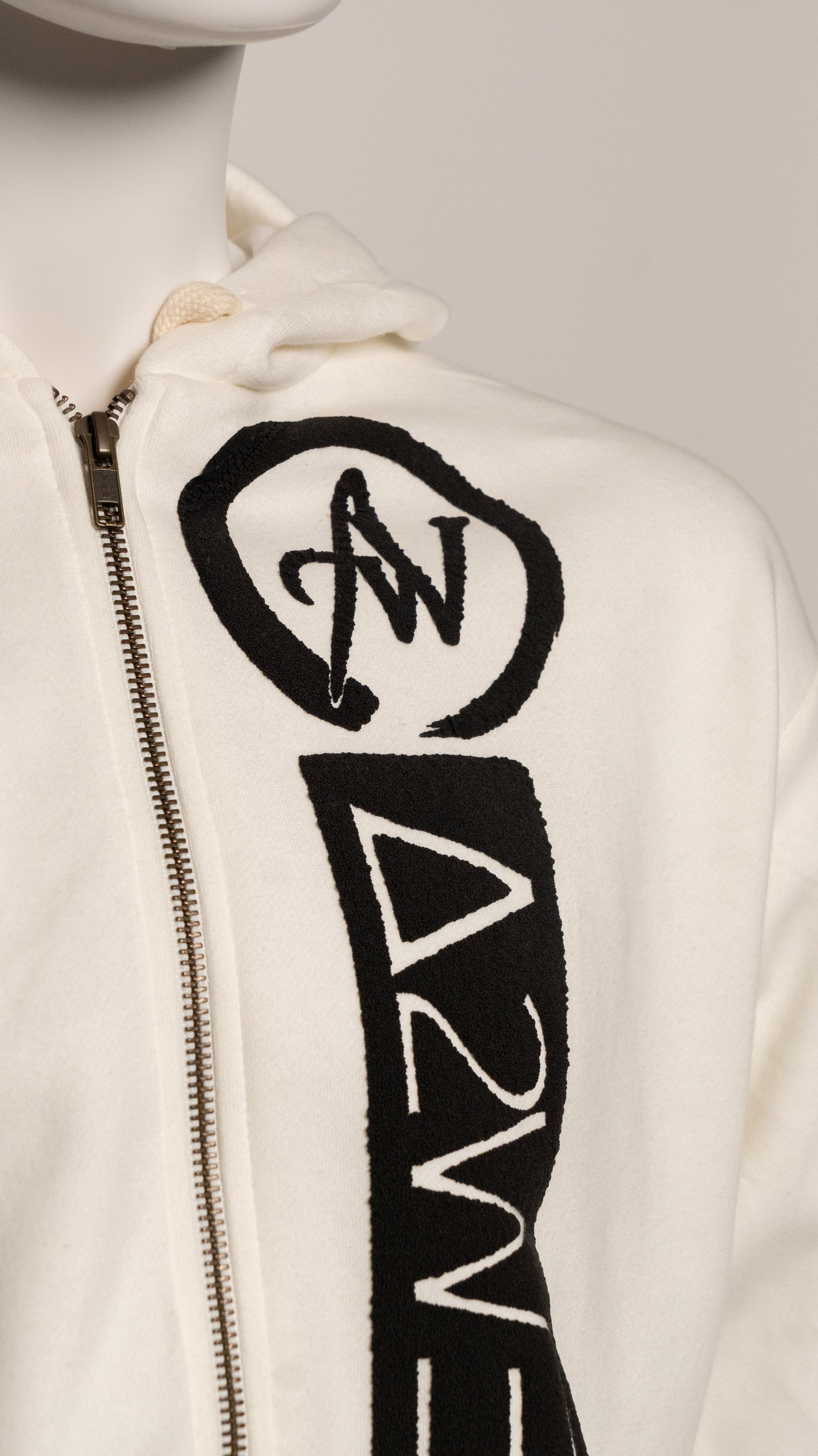 Close-up of a beige hoodie with black logo design on a light gray background