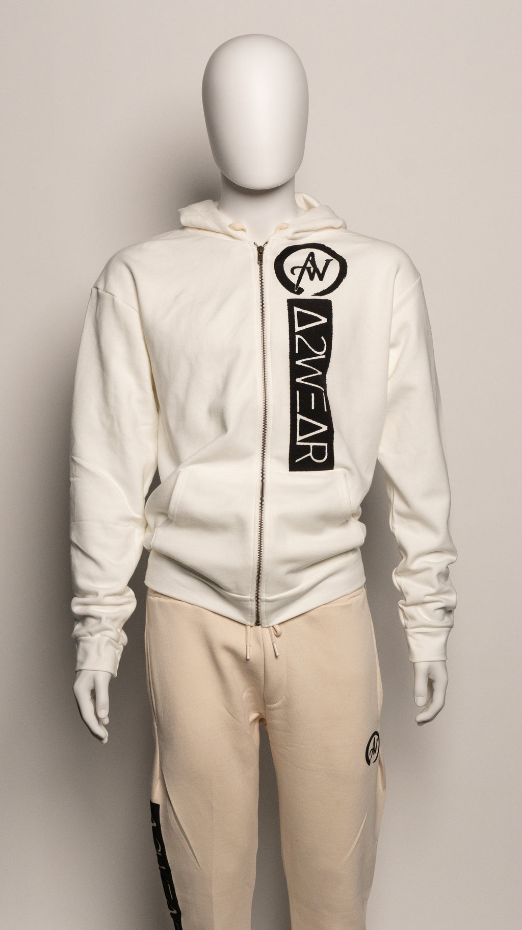 Cream tracksuit with A2W brand logo on a mannequin against a gray background